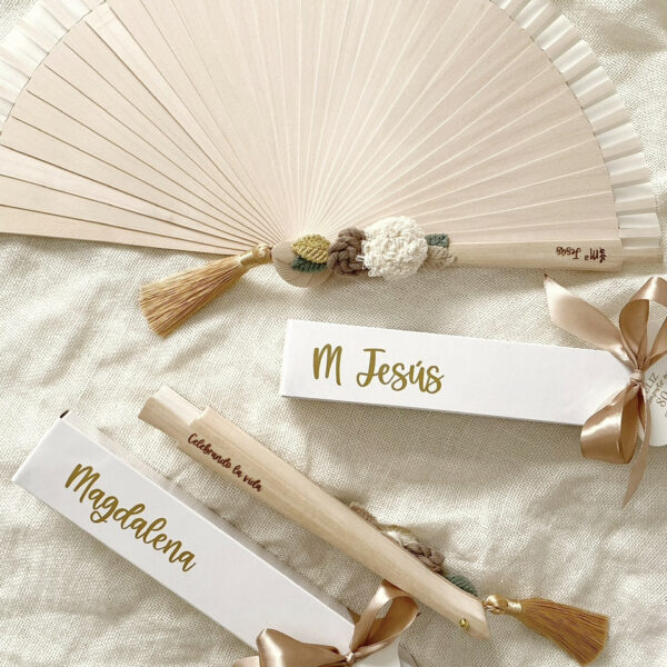 Primer plano de abanico blanco con nombres de los novios y fecha del evento.