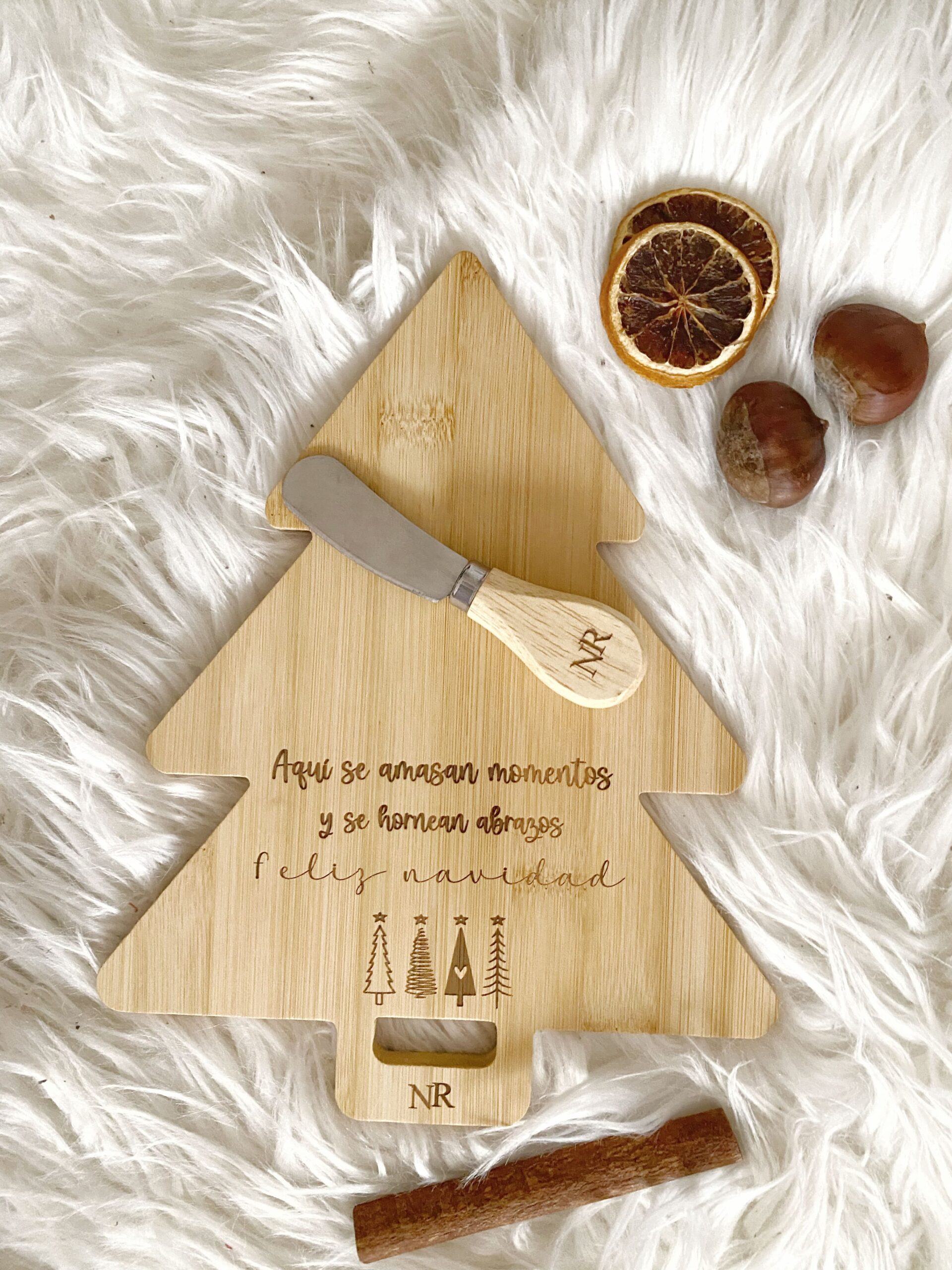 Detalle del grabado de las iniciales personalizadas y la frase navideña en la tabla de bambú.