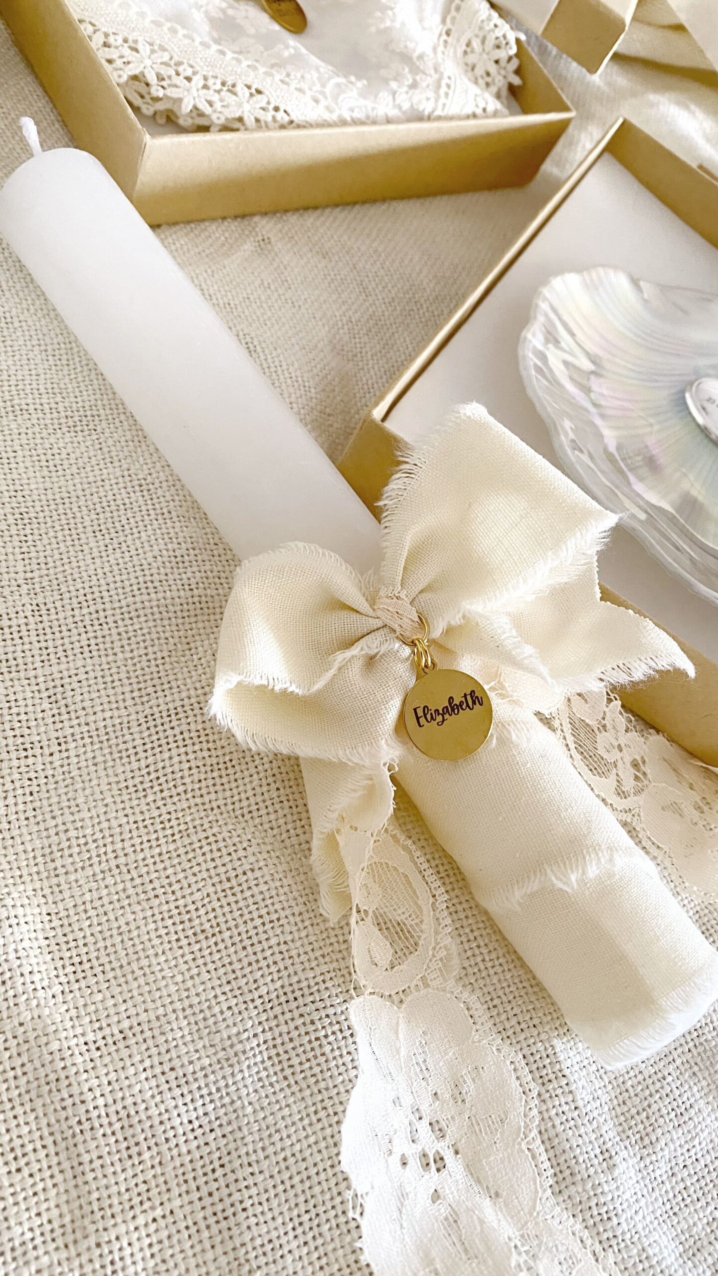 Set elegante compuesto por vela, pañuelo y concha natural preparado para el bautizo.