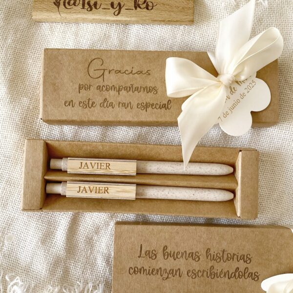 Detalle de regalo para invitados con flores blancas, etiqueta troquelada y soporte de madera grabado.