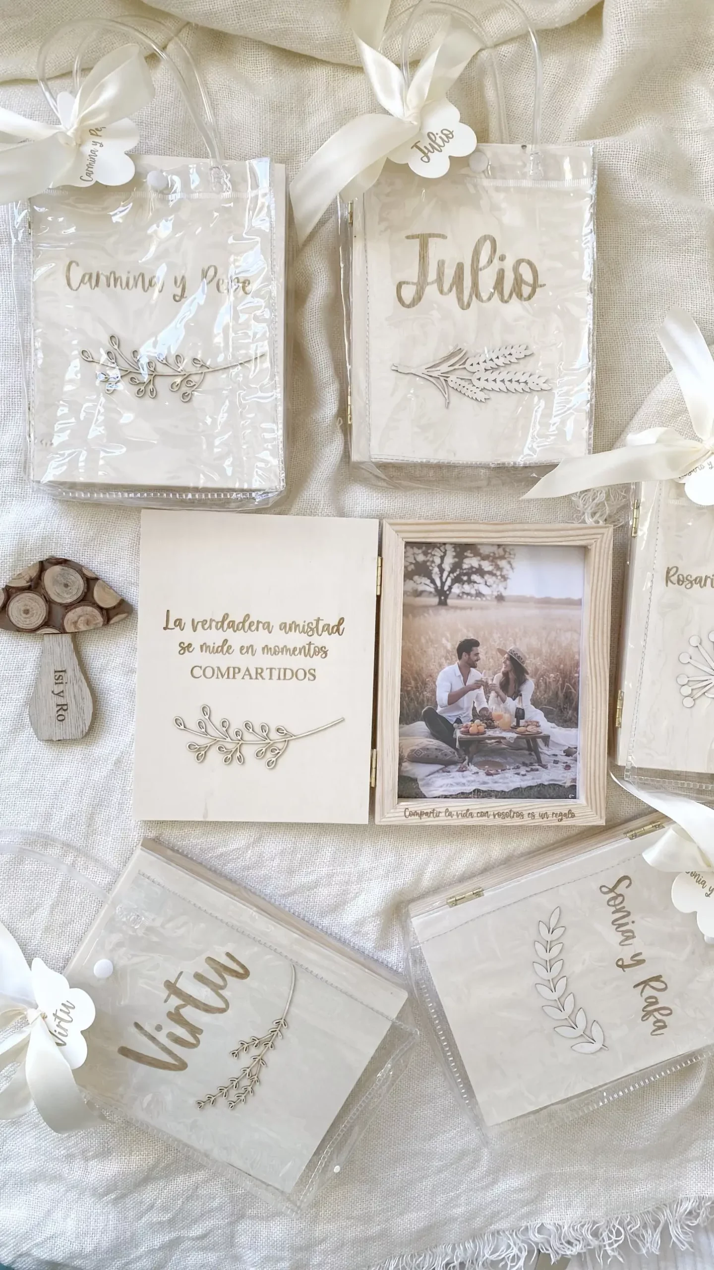 Álbum de madera personalizado abierto rodeado de bolsas de regalo transparentes con lazo y nombre