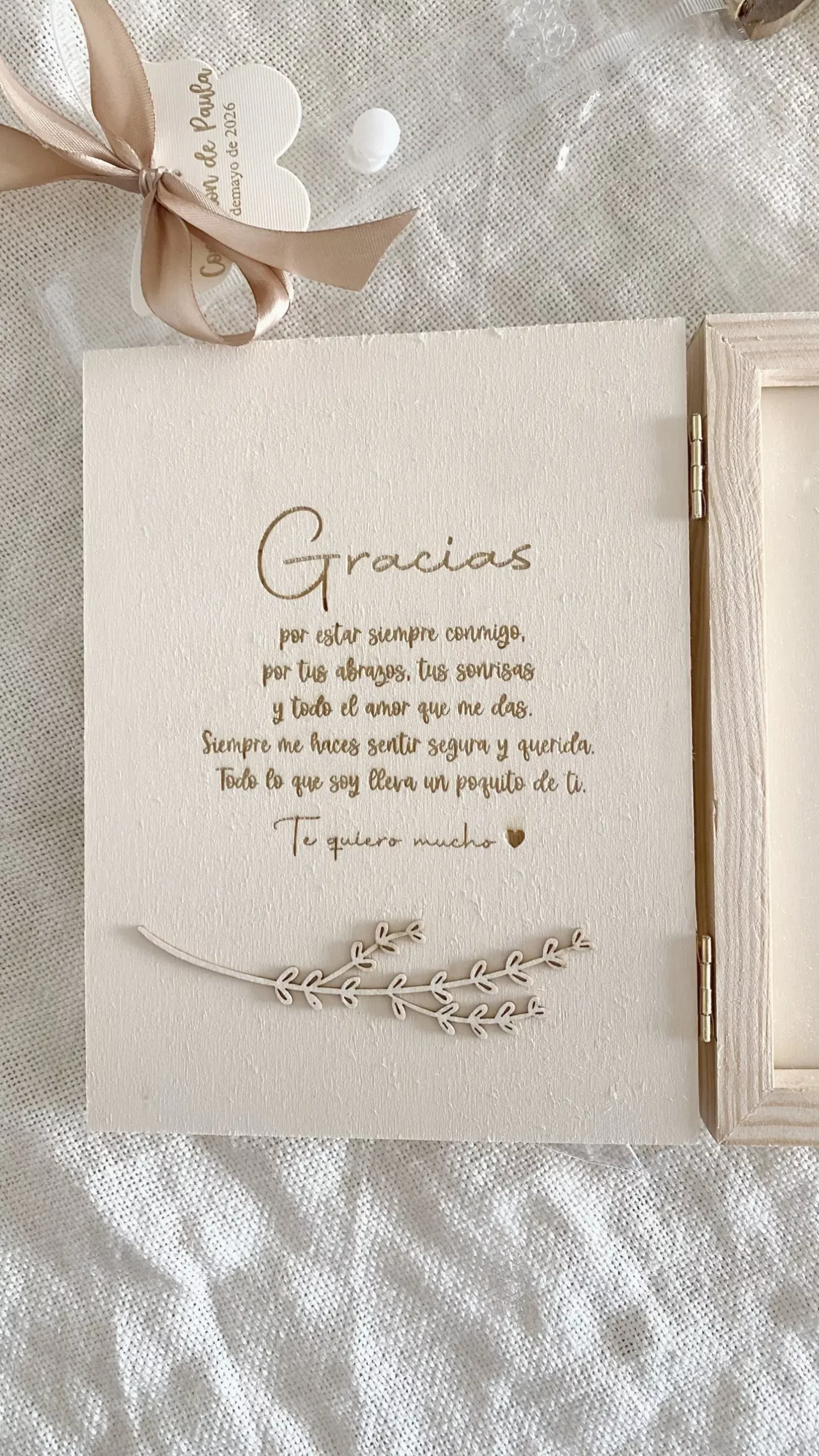 Detalle de la tapa de madera con texto de agradecimiento grabado y ramita decorativa en relieve