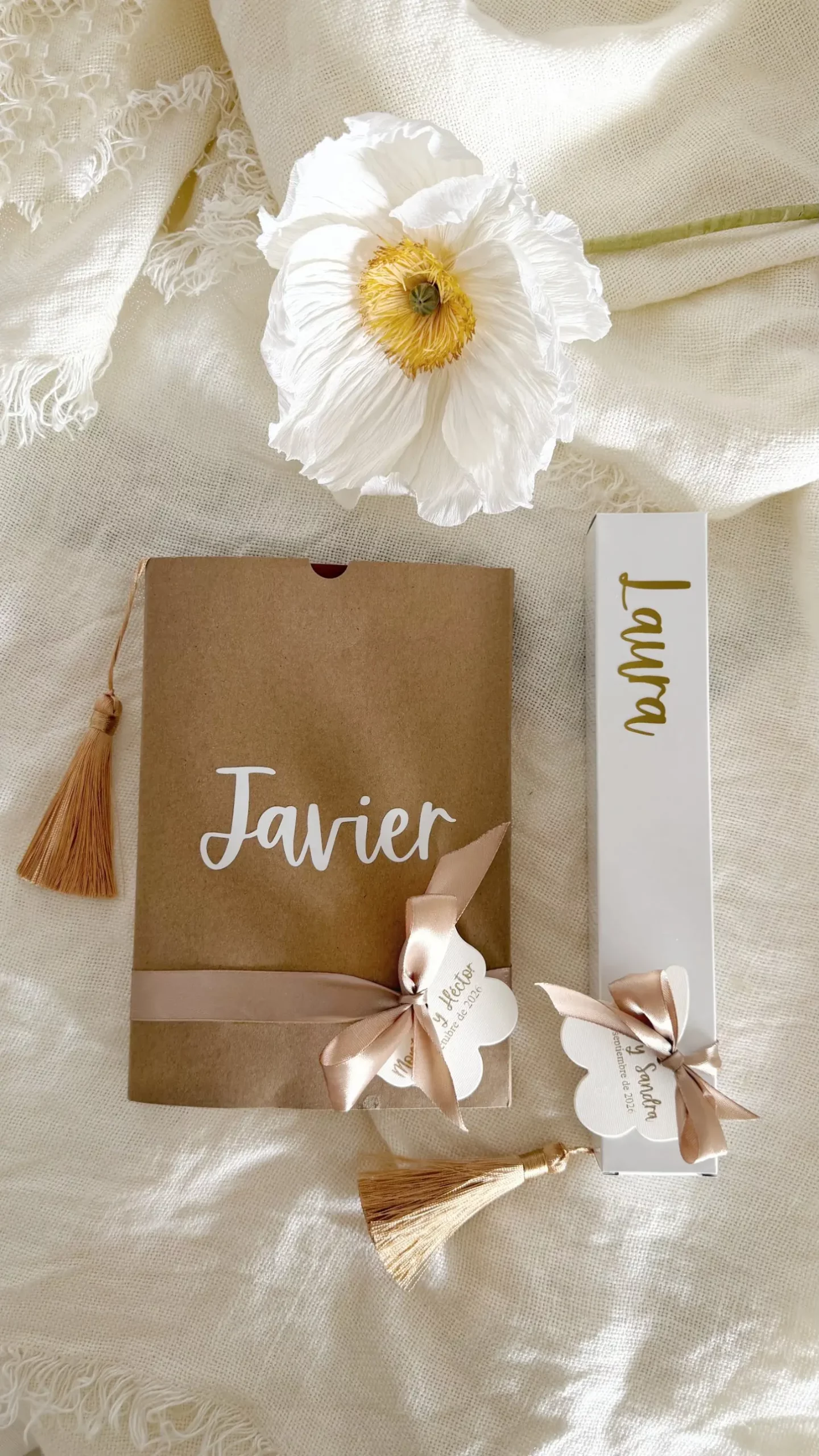 Detalle para invitados: funda kraft del cuaderno personalizado junto a una caja blanca con nombre dorado